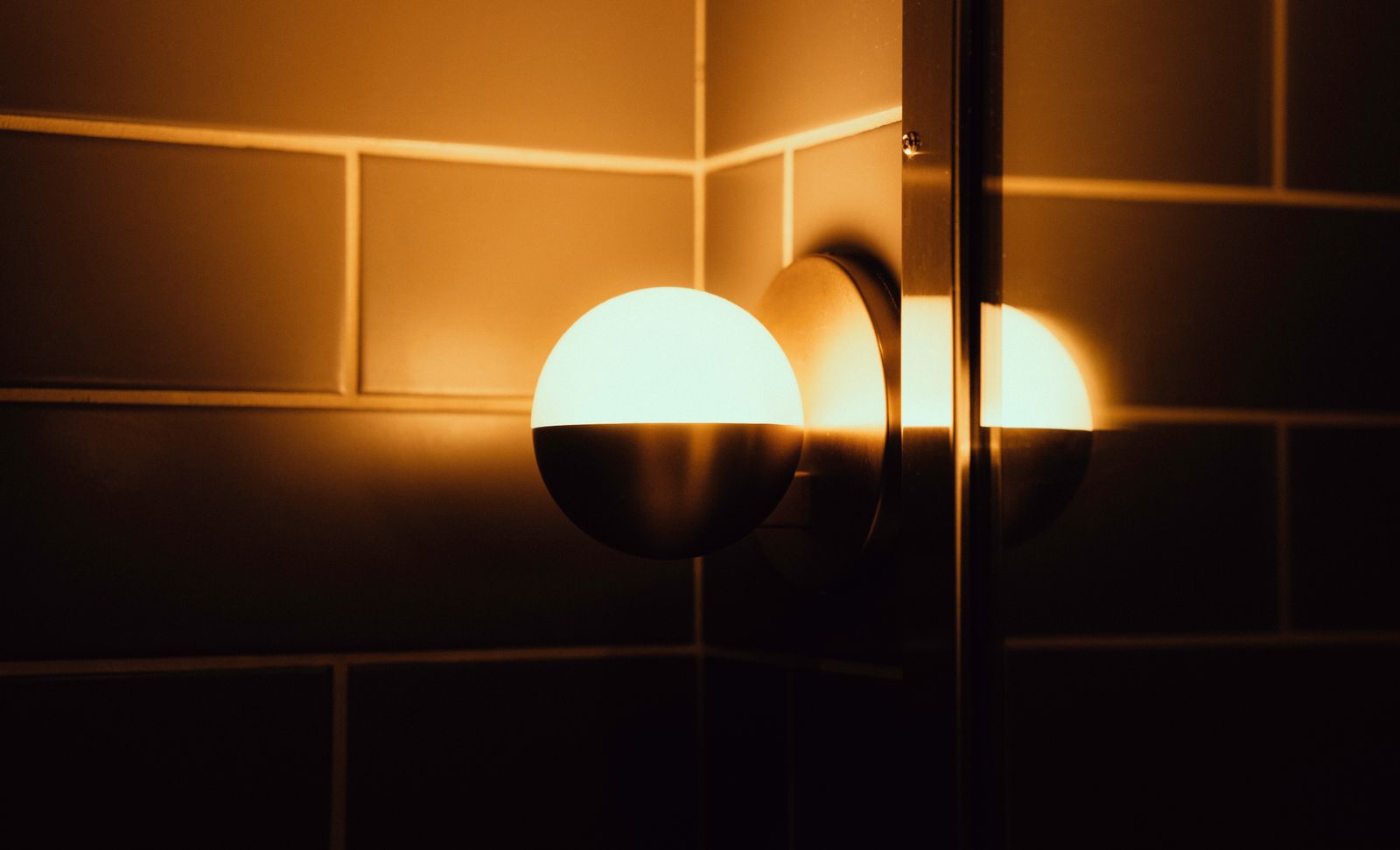 A warm wall light casting a low glow across tiled walls